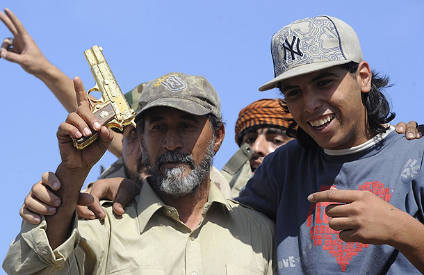 A man holds up Colonel Gaddafi golden gun (Pic: Getty Images)