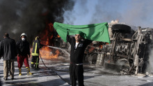 A supporter of Libya's leader, Col. Moammar Gadhafi, holds the Libyan flag at the scene of an accident where an oil tanker truck overturned and caught fire on an overpass in Tripoli, Libya on March 2, 2011. - A supporter of Libya's leader, Col. Moammar Gadhafi, holds the Libyan flag at the scene of an accident where an oil tanker truck overturned and caught fire on an overpass in Tripoli, Libya on March 2, 2011. | Moises Saman/The New York Times