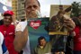 ( Ariana Cubillos / Associated Press ) - A supporter of Venezuela’s President Hugo Chavez cries as she holds a picture of him, as well as a poster of Jesus, during his caravan to the airport in Caracas, Venezuela, Friday Feb. 24, 2012. Chavez bid an emotional goodbye to soldiers and supporters and waved to crowded streets in Caracas on his way to Cuba for urgent surgery to remove a tumor he says is probably malignant. the poster reads in Spanish “I love Chavez.”